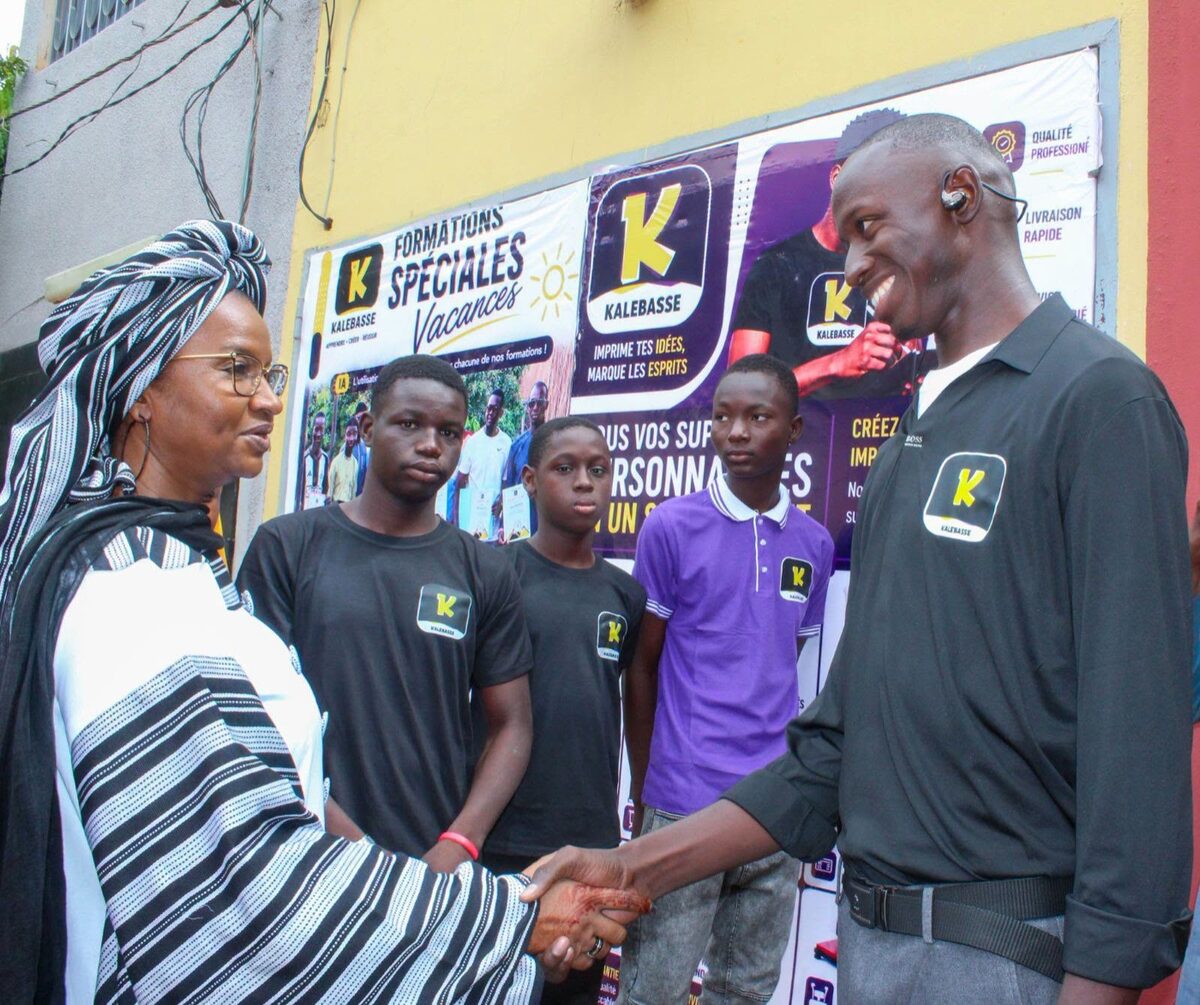 La Ministre Oumou Sall Seck serre la main du jeune promoteur de l'entreprise Kalebasse, entourée des jeunes employés, lors de la visite d'une entreprise bénéficiaire du FACEJ