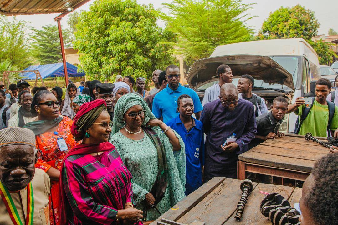 La Ministre Oumou Sall Seck et sa délégation dans un atelier de mécanique automobile de Missabougou, entourées d'apprentis, devant un véhicule en réparation